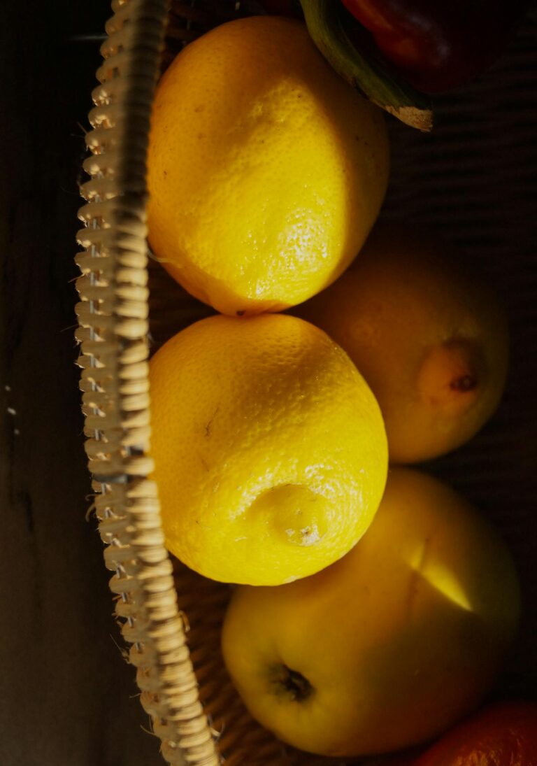 Close-up of vibrant lemons in a wicker basket with warm sunlight highlighting fresh, healthy textures.